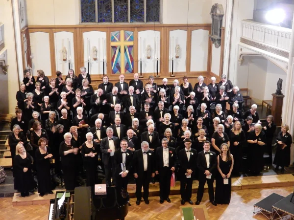 Penzance Choral Society choir members in black concert dress, gathered in rows in a church after a concert